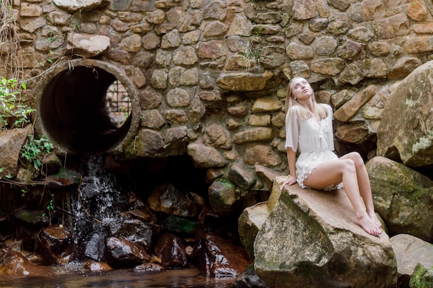 Free photo attractive young woman sitting next to a pipe