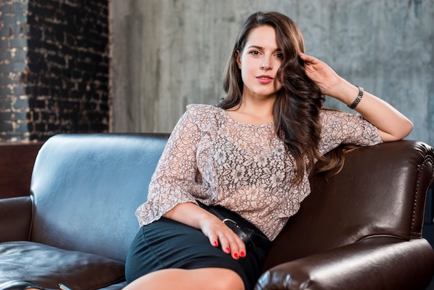 An attractive young woman sitting on sofa looking at camera