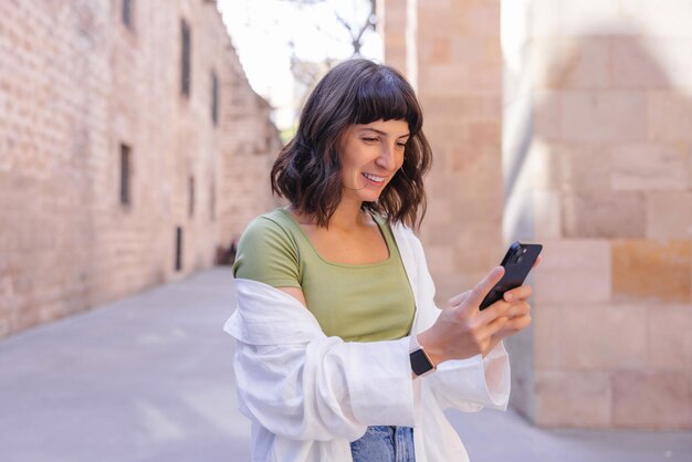 Привлекательная молодая женщина улыбается телефону в городе