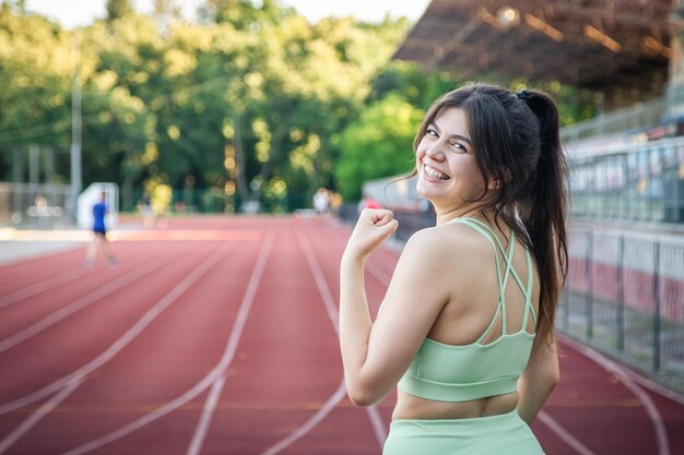 スタジアムでジョギングをしているスポーツウェアの魅力的な若い女性