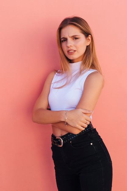 An attractive young woman standing against peach background