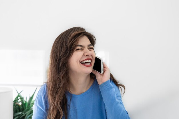 흰색 인테리어 복사 공간에서 전화 통화를 하는 매력적인 젊은 여성