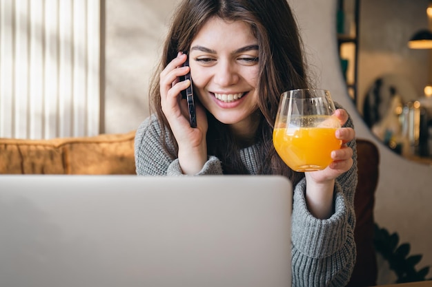 Attractive young woman talking on the phone and working on a laptop