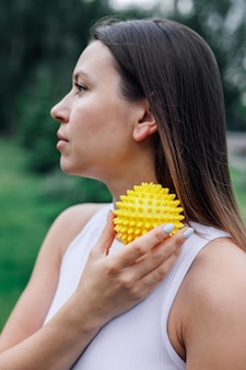 Attractive young woman use spiky massage ball to tighten skin and improve blood circulation in muscl...