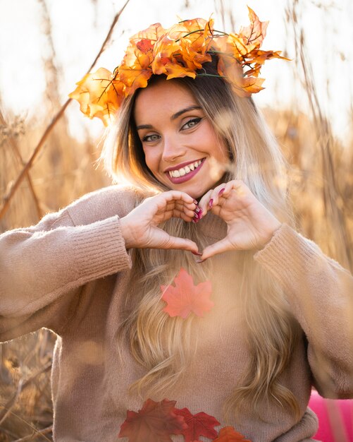 Тиара кленовых листов привлекательной молодой женщины нося делая форму сердца с рукой
