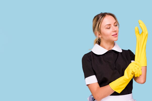 Attractive young woman wearing yellow glove against blue background