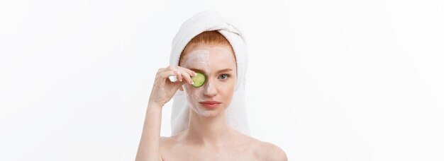 Free photo attractive young woman with beautiful clean skin white mask and cucumbers beauty treatments and cosm