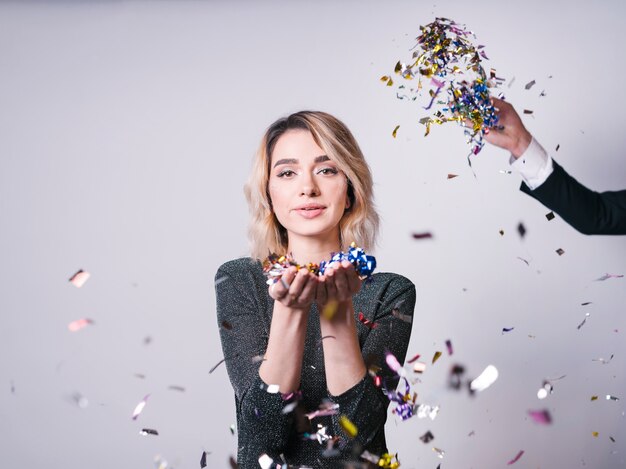 Attractive young woman with confetti near hand tossing tinsel 