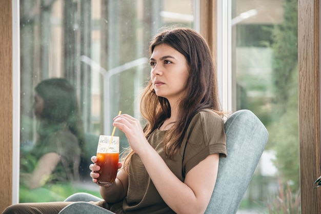 Attractive young woman with espresso tonic drink in cafe interior