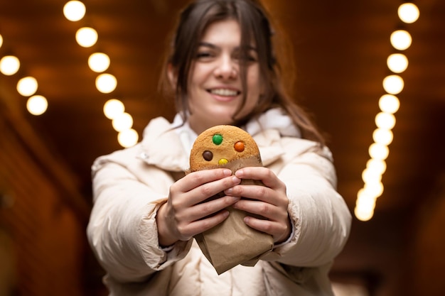 Attractive young woman with gingerbread on a blurred background with bokeh