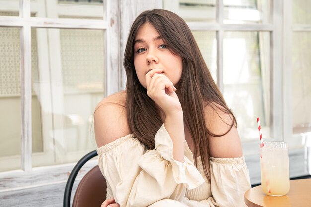 Привлекательная молодая женщина со стаканом лимонада на террасе кафе