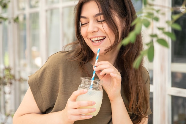 暑い夏の日にレモネードのグラスを持つ魅力的な若い女性