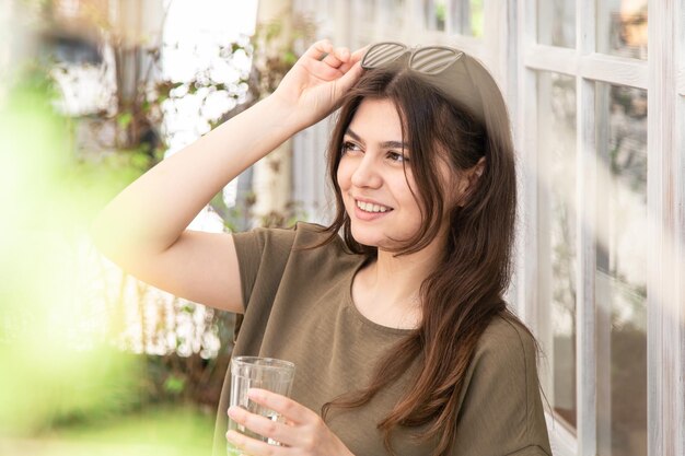 Giovane donna attraente con un bicchiere d'acqua in una giornata estiva sulla terrazza di un caffè