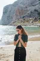 Free photo attractive young woman with hand clasped standing on beach