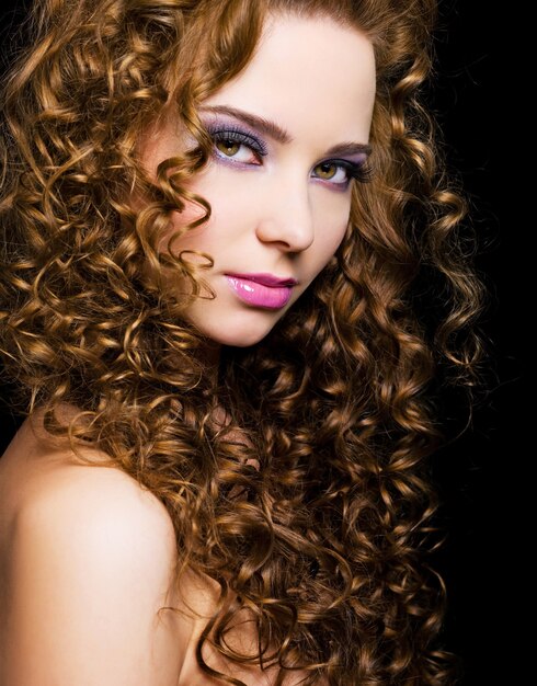 Attractive young  woman with  long ringlet hairs - isolated on black
