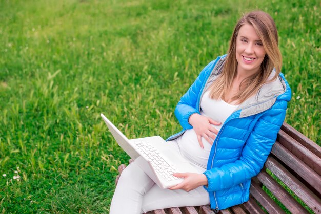 Attractive young woman with toothy smile using laptop outdoors