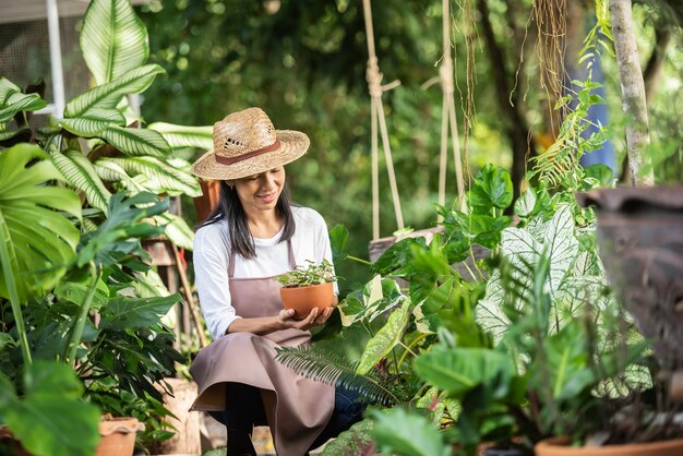 정원 센터에서 장식 식물을 사용하는 매력적인 젊은 여자. 여름 자연에서 외부 원예에 식물을 검사하는 여성 감독자. 웃 고 아름 다운 정원사입니다. 식물 관리.