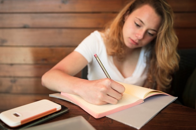 Attractive young woman writing in notebook