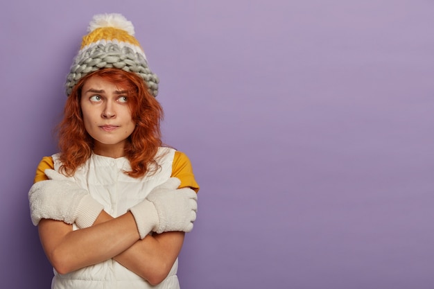 Free photo attractve redhead woman wears warm hat, ski goggles and white jumper