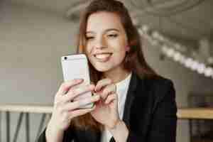 Free photo attrative office lady sitting in cafe with smartphone