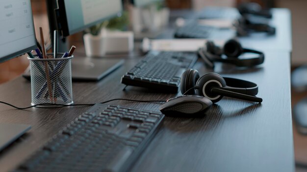 Audio headset used by call center agents to help clients and do telecommunication with technology. Empty customer service workstation with headphones, computers and modern gadgets.