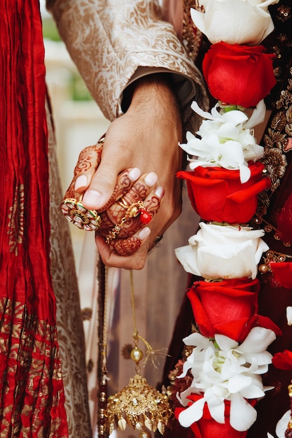 Authentic indian bride and groom's hands holding together in traditional wedding attire