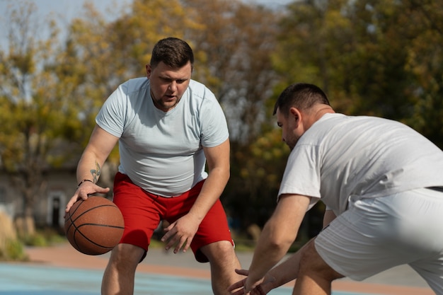 Бесплатное фото Аутентичные сцены мужчин большого размера, играющих в баскетбол