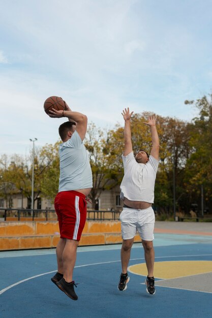 プラスサイズの男性がバスケットボールをしている本物のシーン