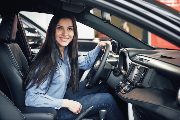 Автобизнес, продажа автомобилей, потребительство и люди концепции - счастливая женщина, принимая машину от дилера в автосалоне или салоне