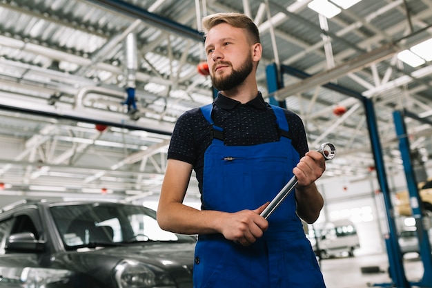 Free photo auto mechanic holding big spanner