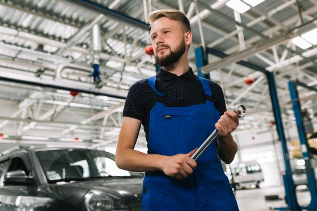 Auto mechanic holding big spanner 