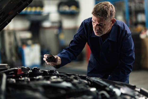 Auto mechanic opening radiator cap while repairing car in a repair workshop