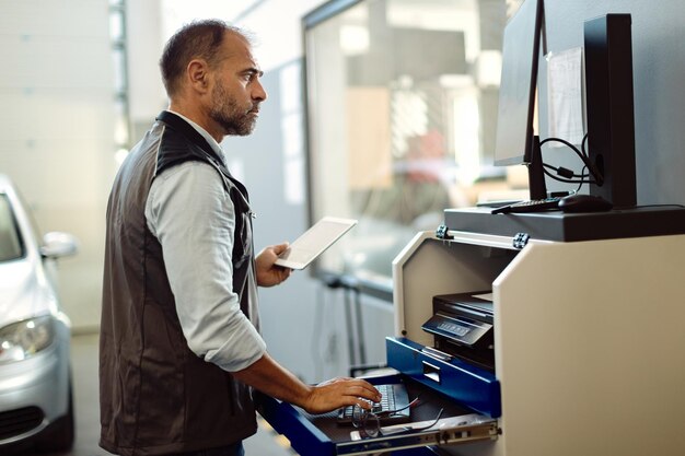 Auto mechanic using touchpad and desktop PC while working in a repair shop