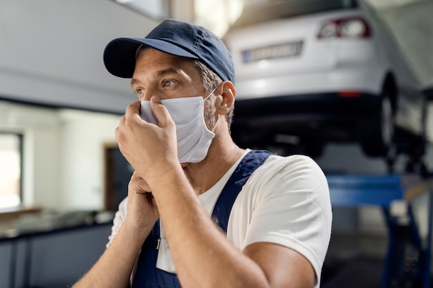 Auto repairman adjusting face mask in a workshop due to COVID19 pandemic