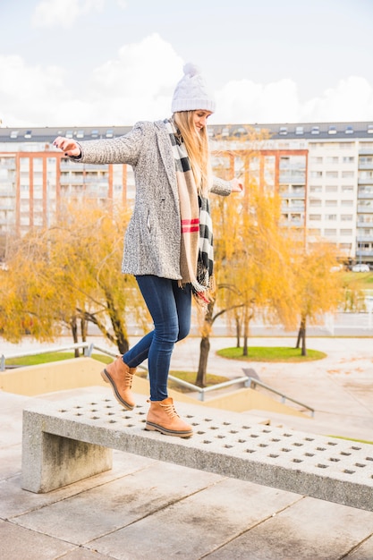 Free photo autumn clothed woman balancing stone bench