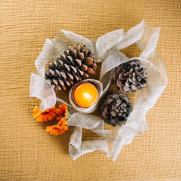 Decorazione autunnale con candele e coni di pino