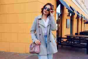 Free photo autumn image of stylish charming female in beige coat walking outdoor. fashionable street look.