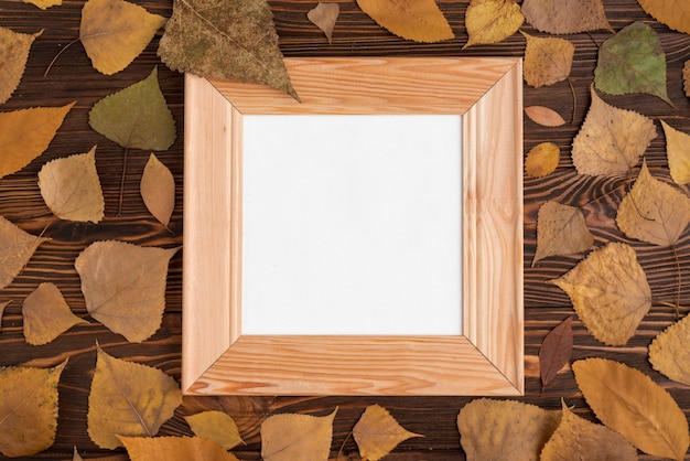 Free photo autumn leaves around frame on table