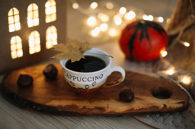Осенний натюрморт с чашкой кофе, тыквой и листьями на уютном фоне
