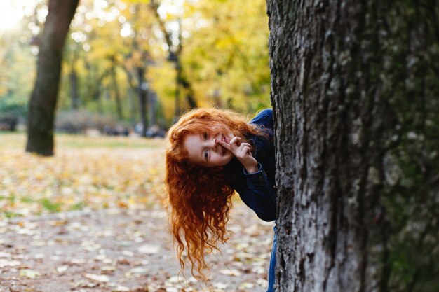 秋の雰囲気、子供の肖像画。魅力的で赤い髪の少女は、歩いているとtで遊んで幸せそうです