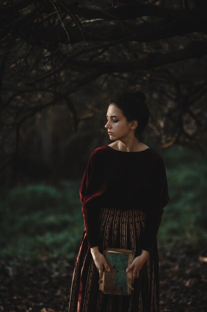 Autumn vibes. Gothic style. Brunette woman in dark red cloth