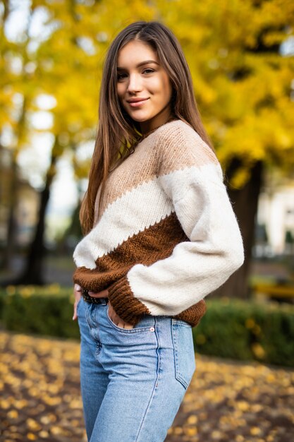 Autumn woman in sweater in autumn park. Warm sunny weather. Fall concept
