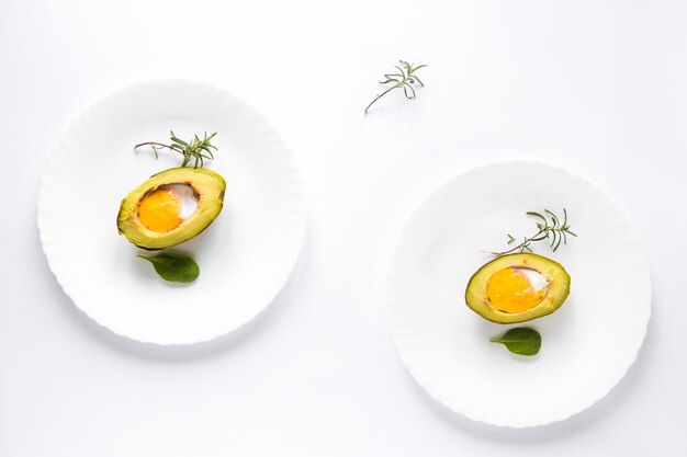 흰색 배경 위에 접시에 계란으로 구운 아보카도