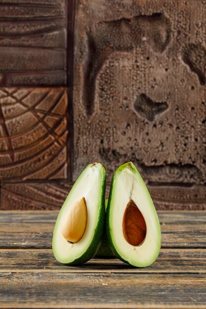 Avocado halves on old wooden and stone tiles. side view.