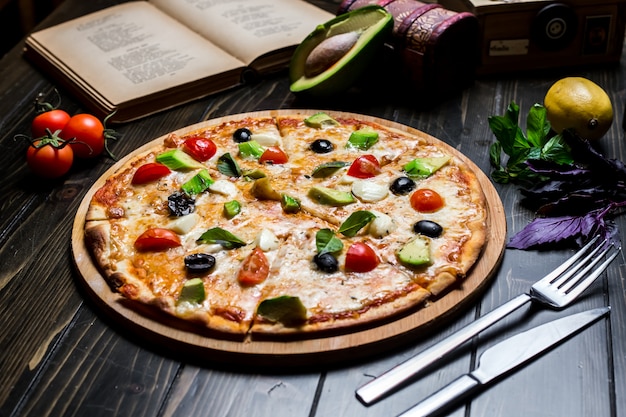 Vista laterale delle olive delle spezie del basilico del pomodoro del formaggio della pizza dell'avocado