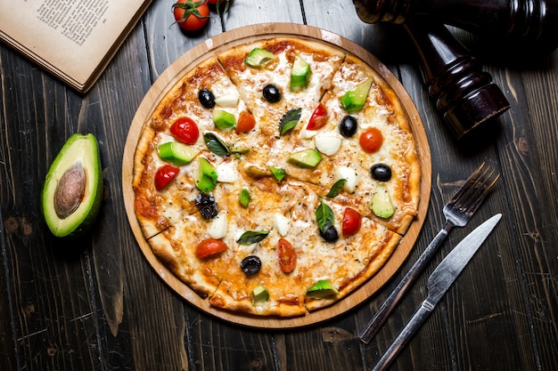 Avocado pizza cheese tomato basil spices olives top view