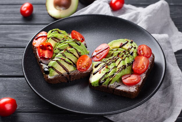 Avocado toast for breakfast on plate with tomatoes and sauce