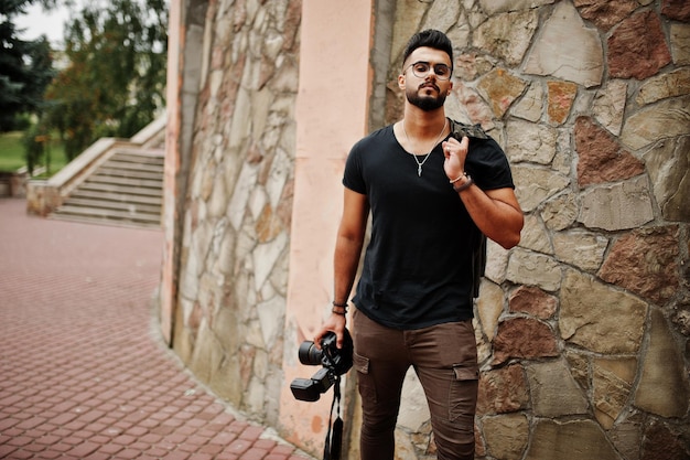 Awesome beautiful tall ararbian beard macho man photographer in glasses and black tshirt with professional camera at hands