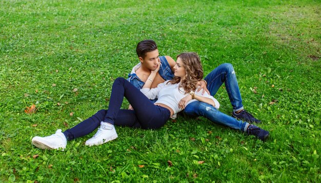 Awesome casual couple lying on field of grass in the park.