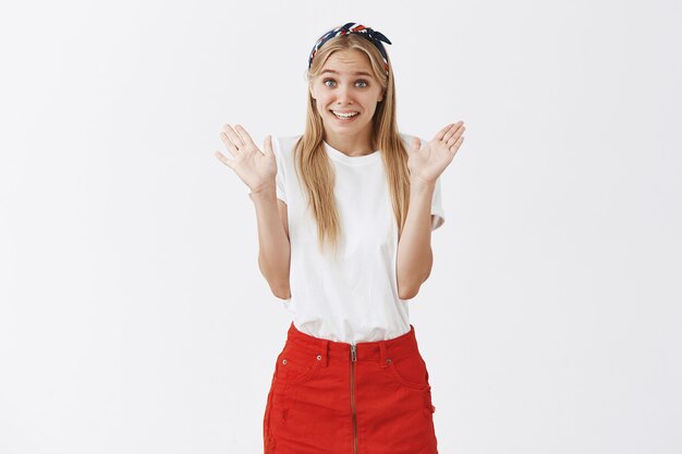 Awkward cute young blond girl posing against the white wall